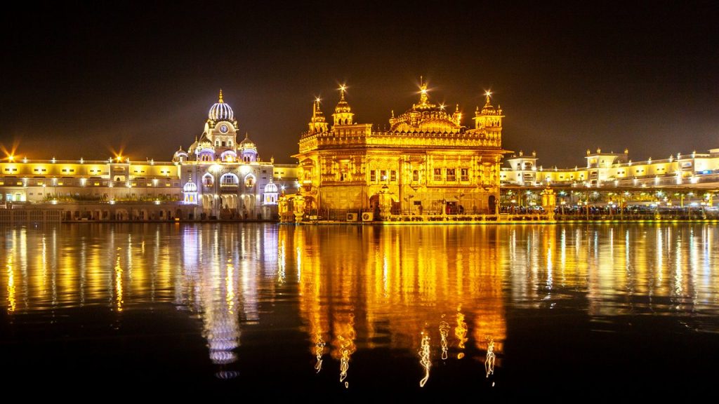 Templo Dorado de Amritsar iluminado de noche y reflejado en el agua